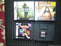 Photo showing three Nintendo DS game cases and one loose game cartridge: Call of Duty 4 Modern Warfare, Endwar, and Spectrobes Beyond the Portal.