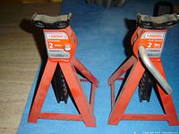 Photo showing the two orange 2 ton rated axle stands with adjustable saddle tops and ratchet mechanism.