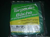 Photo of sealed woven polyethylene tarpaulin in green and yellow packaging, showing label with size and features.