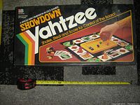 Photo showing the top of the Showdown Yahtzee game box with artwork of the game board and pieces.