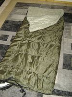 Photo of the Coleman brand sleeping bag laid out on a carpeted floor, showing the exterior and interior liner, indicating usage and condition.