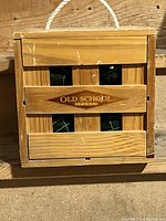 Wooden crate-style case with rope handle containing four bocce balls, front view showing Old School Sports logo.