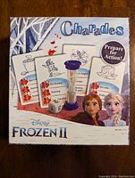 Box front of the Frozen II themed charades game showing cards, die, and timer, with characters Anna and Elsa on box.