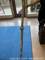 Two Nordic Track Topline Air cross country skis standing upright indoors on a blue mat, showing one ski front view with bindings visible, seller holding top of ski.
