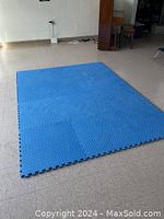 Blue foam mats connected and laid flat on a tiled floor showing the textured surface and puzzle edges.