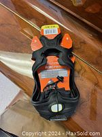 Image of one Ice Trax ice grip in size small/medium, black rubber with orange cleats, showing top view with packaging label.