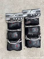 Set of knee, elbow, and wrist protective pads by Pulp in black with grey and red accents. Packaging tags visible.