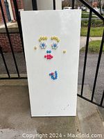 Photo of the rectangular white magnet board with various colorful round magnets arranged in a pattern resembling a face.