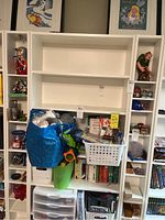 View of both narrow white display shelves filled with various items not included in sale, showing overall structure and size.