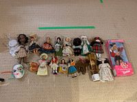 Layout of all dolls including vintage porcelain dolls, assorted vintage dolls, porcelain mask, and small cogs and doll stands