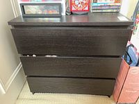 Front view of the dark brown dresser showing three closed drawers.