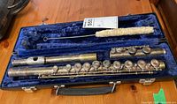 Full view of Emerson flute disassembled in open blue velvet-lined carrying case alongside cleaning rod with brush.
