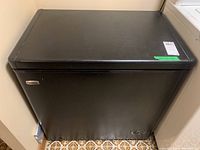 Front view of black Danby Premium chest freezer with minor surface scratches and dents.