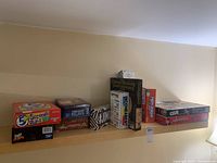 View showing multiple board games and party games lined on a shelf including 5 Second Rule, Forbidden Island, Jenga Quake, Monopoly, Chinese Checkers, Clue, Sushi Go Party, Party Charades, and others.