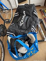 Photo showing black Easton hockey bag with visible logo, blue bag with kids hockey gloves, pants, and other gear inside