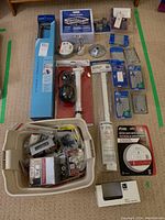 Overview photo showing main items including the tall fixture box, plumbing parts, towel bar, smoke detector, switch and outlet covers, and assorted hardware in a bin.
