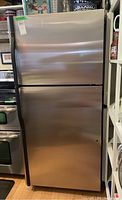 Front view of stainless steel refrigerator showing top freezer and main door