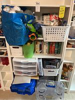 Four shelves filled with children's books, toys, stuffed animals, Beyblades, magic set, and coin collecting materials