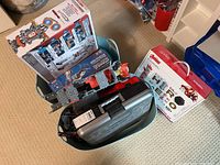 Overview showing multiple Meccano sets including Meccanoid robot box, Marvel Avengers Hero Inventor Kit box and additional items in a storage container.