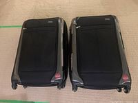 Top view of two black Ricardo Elite travel suitcases side by side on carpet showing front soft panel and wheels.