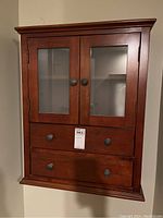 Full front view of the wall cabinet showing two frosted glass doors and two drawers below with round knobs.