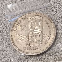 Front side of the 1958 Canadian silver dollar coin showing the British Columbia Totem design and dates 1858 and 1958.