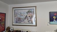 Framed art print hanging on wall in living space with other decor.