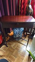 Front view of dark wooden Bombay side table with pull-out drawer, showing smooth surface and decorative scroll detail on drawer front.