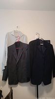 Three items hanging on wall: Loro Piana striped shirt, Europa gray pinstripe blazer, Jones New York black tuxedo jacket