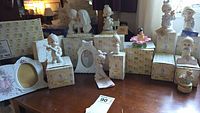 Wide view of multiple Precious Moments figurines displayed on a table, some on original boxes