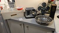 Full view of lot with toaster, fan, glass bowl, fluted cake pan, and white appliance with glass bowl