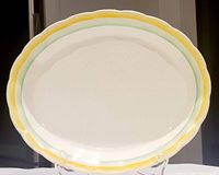 Full view of oval platter with cream base and scalloped edge featuring yellow and green borders.