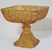 Side angle of amber glass compote showing detailed Daisy & Button pattern and pedestal base