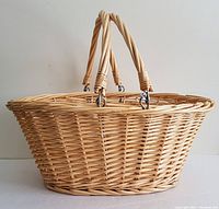 Full side view of the oval natural wicker laundry basket with two handles upright.