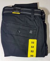 Folded black Buffalo David Bitton cargo shorts with visible side and back flap pockets and attached woven belt, showing size label 32.
