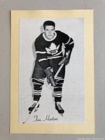 Front view of the black and white hockey photo of Tim Horton mounted on cream cardboard, showing the full image and signature.