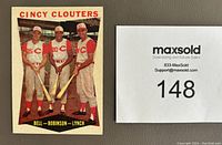 Close-up of 1960 Topps Cincy Clouters baseball card showing three players in uniform holding bats (Bell, Robinson, Lynch) with numbered MaxSold tag