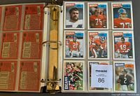 Binder open with multiple 1987 Topps Football cards displayed in plastic sleeves, including Broncos and Bears players.