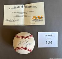 Photo showing signed baseball, certificate of authenticity, and lot number card.