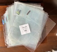 Stack of clear Ultra Pro Platinum 9 card sheets with holographic branding stickers, showing multiple used sheets for card storage.