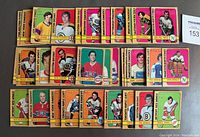Photo of 42 hockey cards from the 1972-73 OPC series spread on a table showing front card views. Various NHL players from different teams with colored borders. Writing visible on the front on some cards.