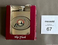 Montreal Expos stainless steel hip flask in original red and white box with clear plastic front panel, showing the flask inside.