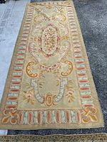Full view of the needlepoint carpet showing overall floral and stylized French pattern with beige background and multi-color details.