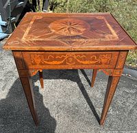 Front view of antique Italian walnut table showing detailed marquetry on apron and tapered legs.