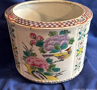 Side view showing pink and purple flowers with yellow bird and green leaves, gold trim at top.