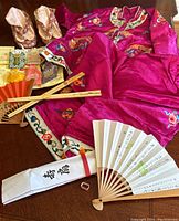 Full lot showing child's magenta handmade kimono-style outfit, traditional slippers, folding fans, and assorted charms.