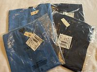 Two Talbots sweater sets in original clear plastic bags, showing light blue and dark blue sweaters with tags attached.