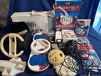 Overview of all items including two steering wheels, game discs, sensor bar, and power adapter with cables.