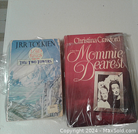 Photo showing front covers of both books wrapped in plastic, The Lord of the Rings on the left, Mommie Dearest on the right.
