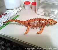 Side profile view of fully assembled wooden dinosaur puzzle showing its shape, legs, tail, and head skull details.